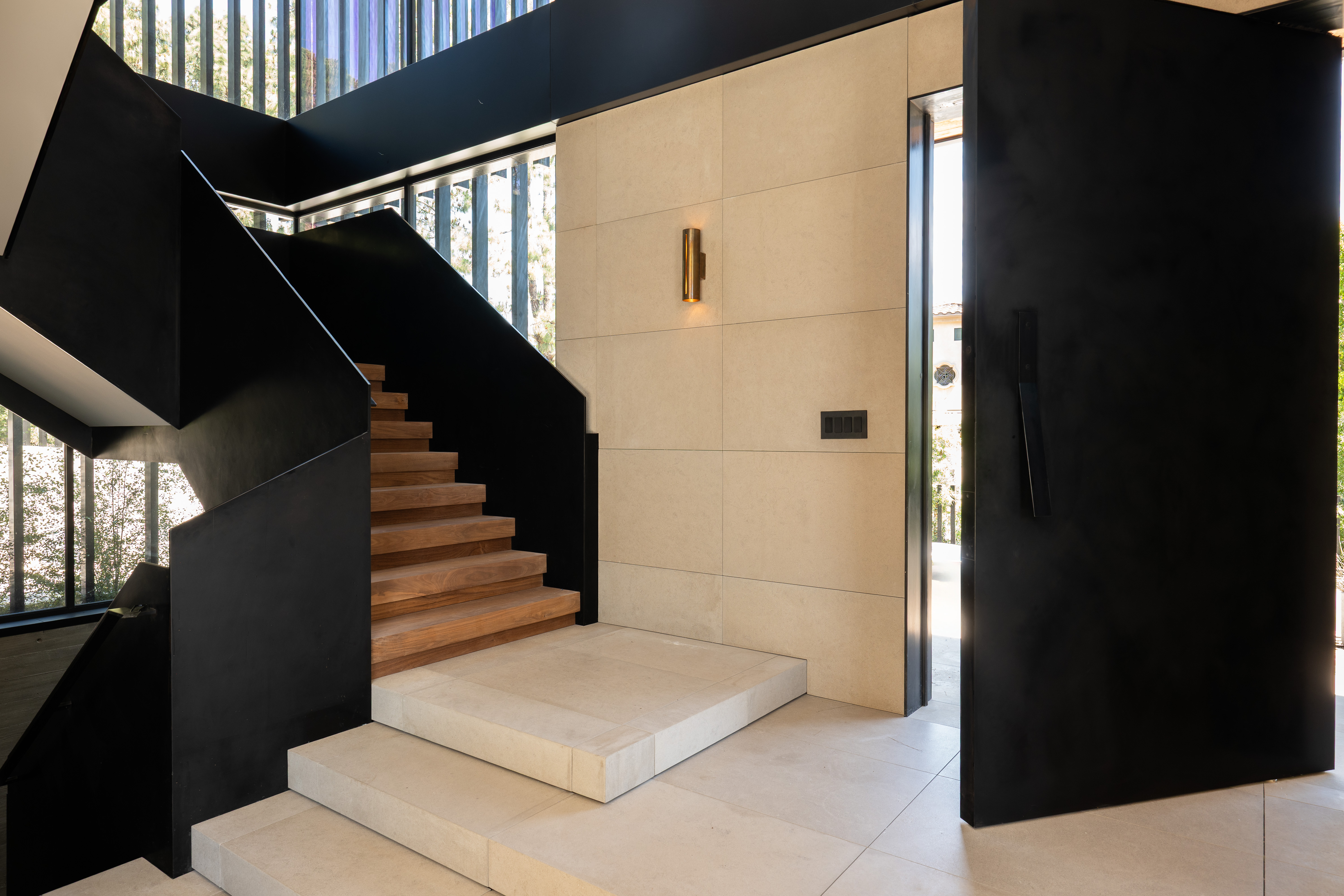 Entry foyer — steel stair, limestone, brass sconce