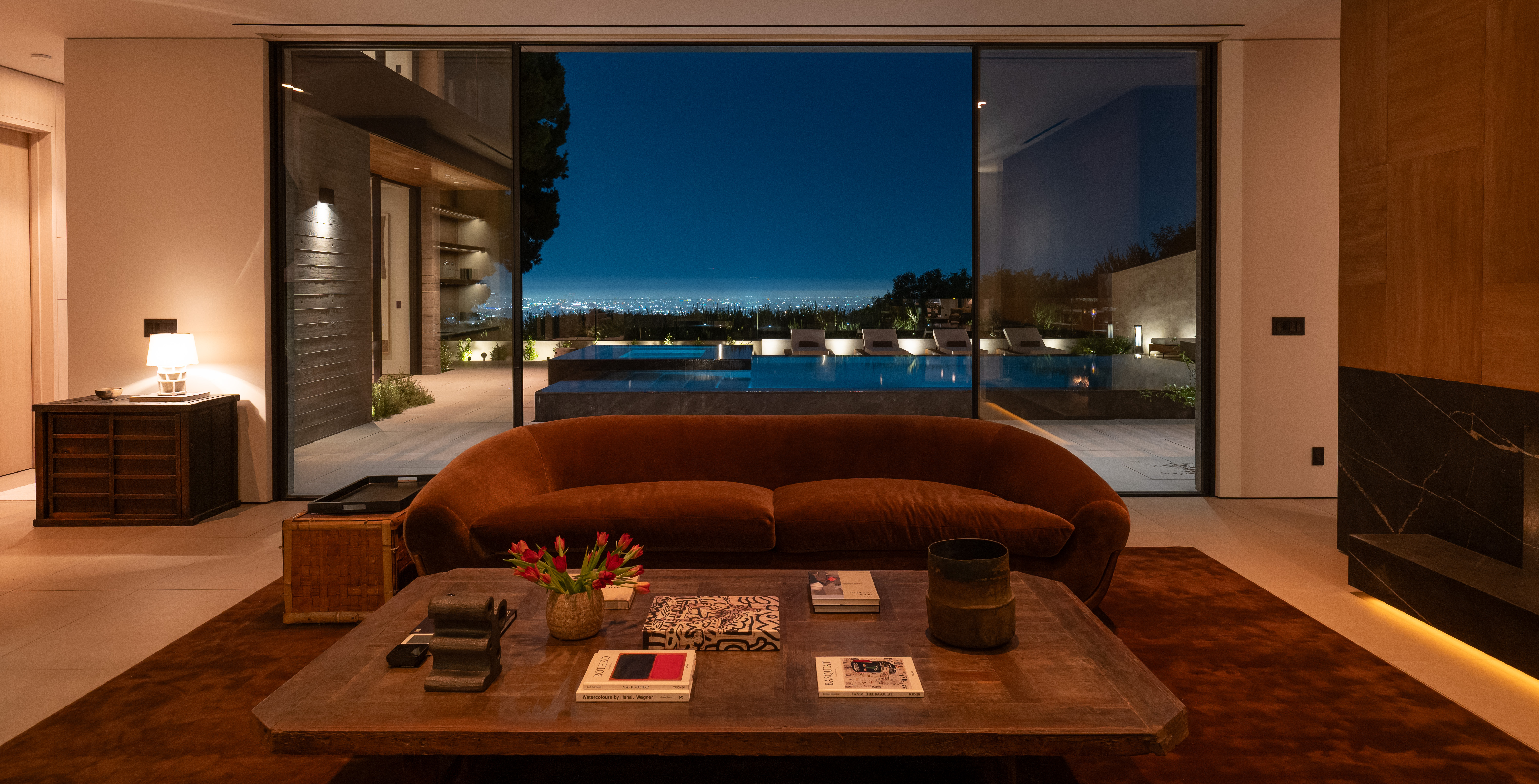 Living room at dusk — pool beyond, warm-dim cove lighting